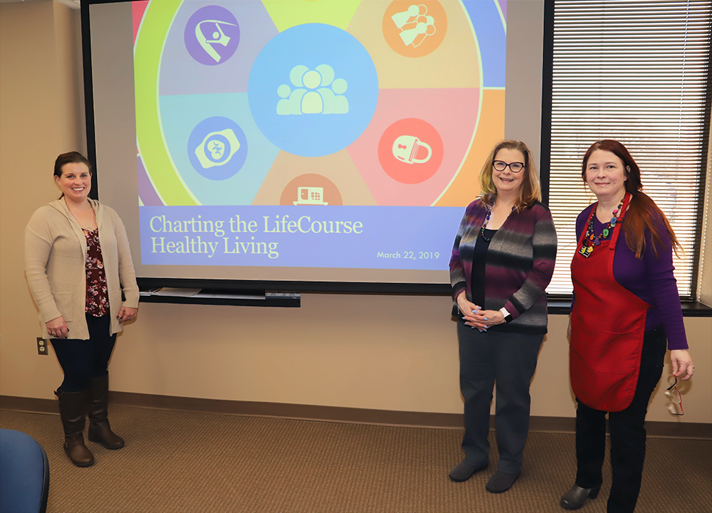 In this photograph, Crystal Bell, Jane St. John, and Terri Jordan of "The Color Coded Chef" stand in front of a projection of their presentation.