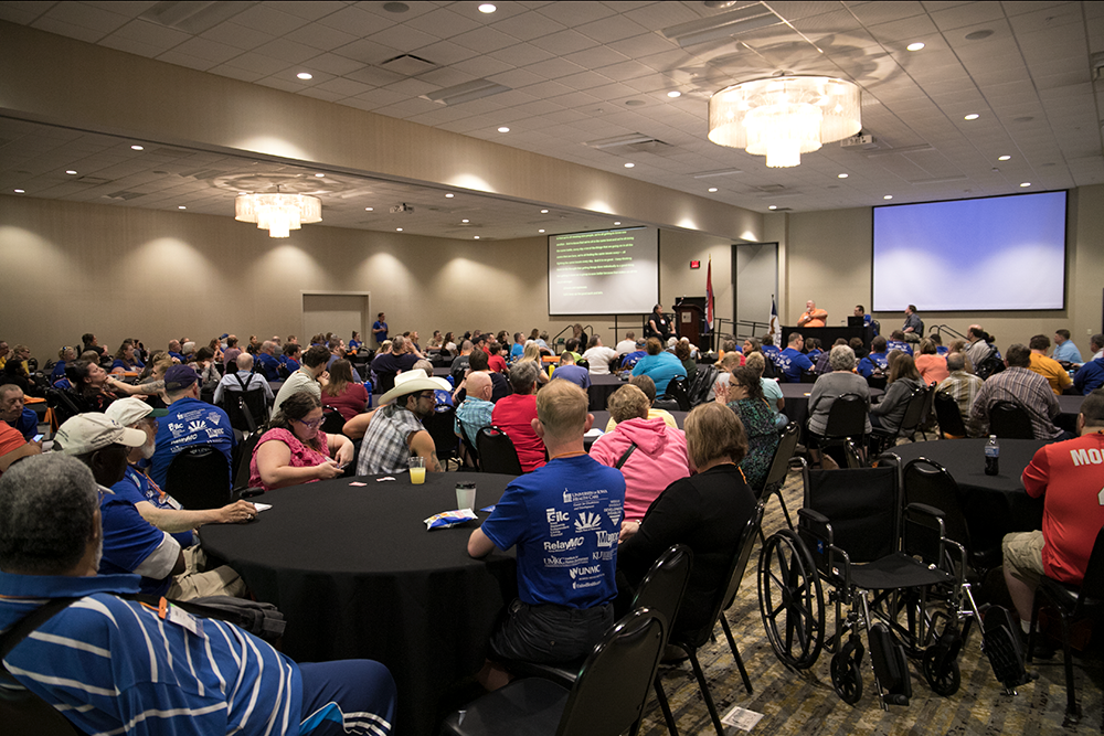 This picture shows SOAR Conference attendees sitting at round tables in a ballroom and listening to a panel of speakers.